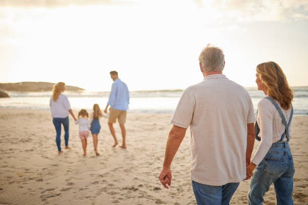 Three generations of family walking together along the beach at sunset